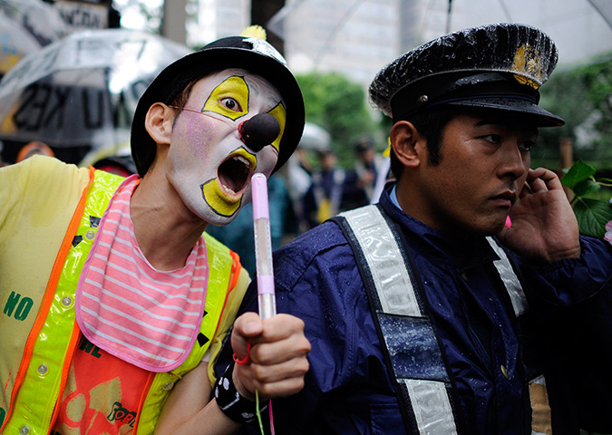 Japan nuclear protests: A protester with radioactivity make up performs next to a policeman