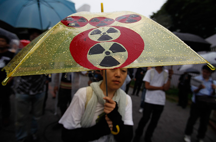 Japan nuclear protests: A protester holding an umbrella with altered Tokyo Electric Power Co logo