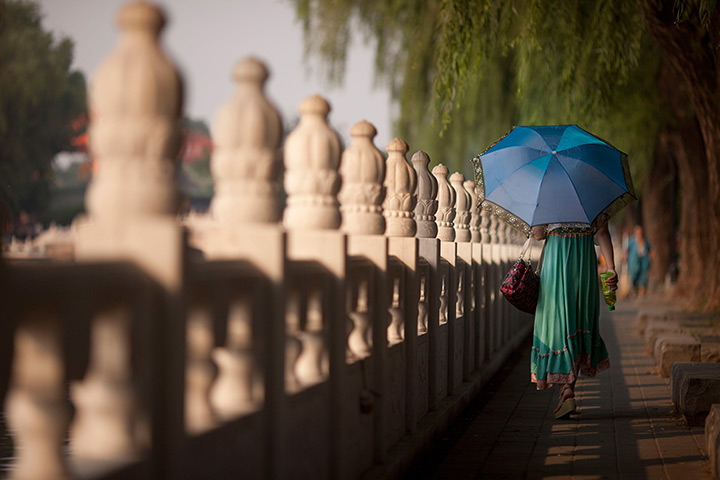 24 hours: Beijing, China: A woman walks with an umbrella 