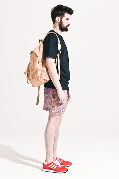 All Ages: Male model wears black sweat top and paisley swimming trunks