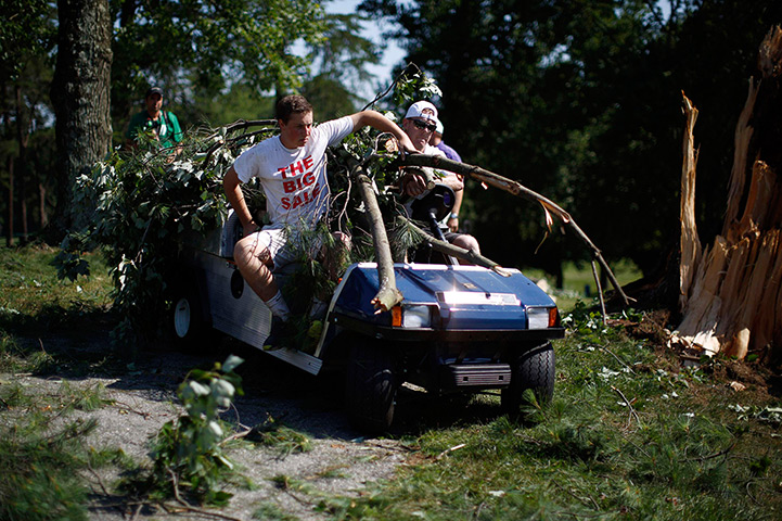 US storms: Workers ride in a golf cart overloaded with tree branches