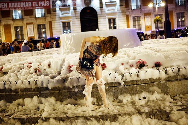 24 hours in pictures: A demonstrator gets out of a fountain full of foam in Madrid