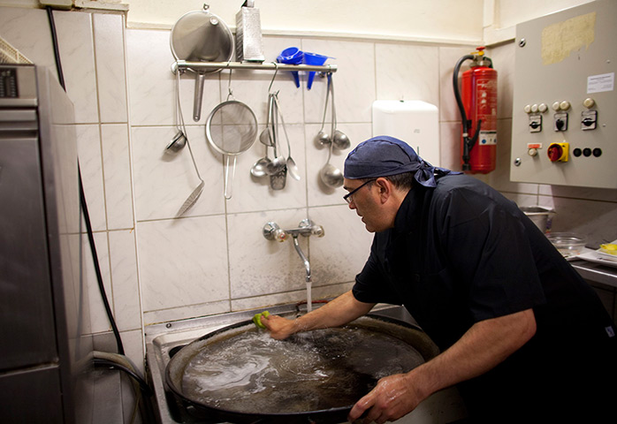From the agencies: Jose Manuel Abel washes a paella pan while working as a kitchen assistant