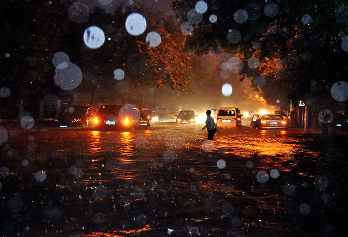 Beijing flooding: A woman wades through a flooded street