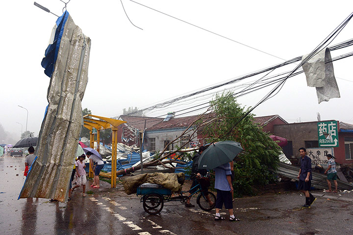 Beijing flooding: Commuters make their way home past roadside debris as a storm hits Beijing