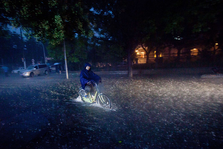 Beijing flooding: A cyclist rides through a flooded street