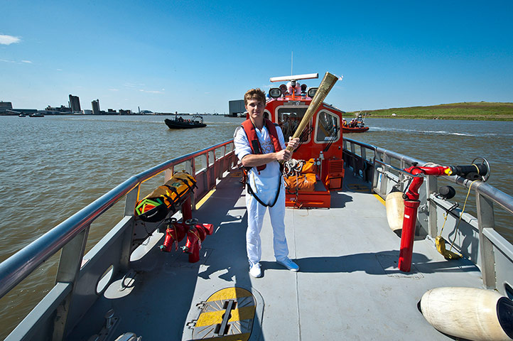 Olympic Torch 65: Aaron Reynolds carrying the Olympic Flame on a London Fire Brigade Boat