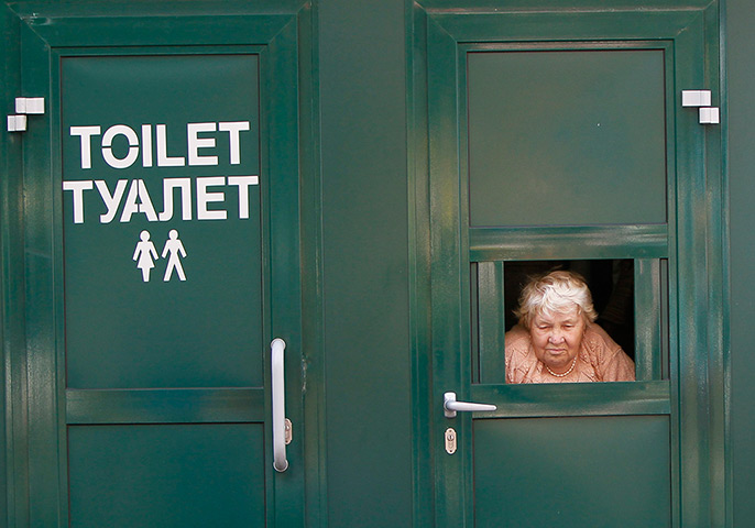 24 hours in pictures: A cashier awaits clients as she sells tickets to a public toilet