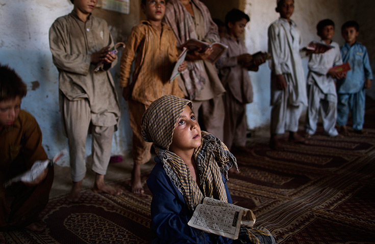 24 hours in pictures: Pakistani boy listens to his teacher reading the Quran