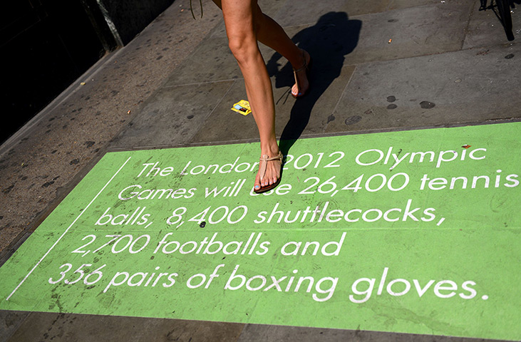 Olympic week update: A woman walks over a sign giving Olympic facts painted on a pavement