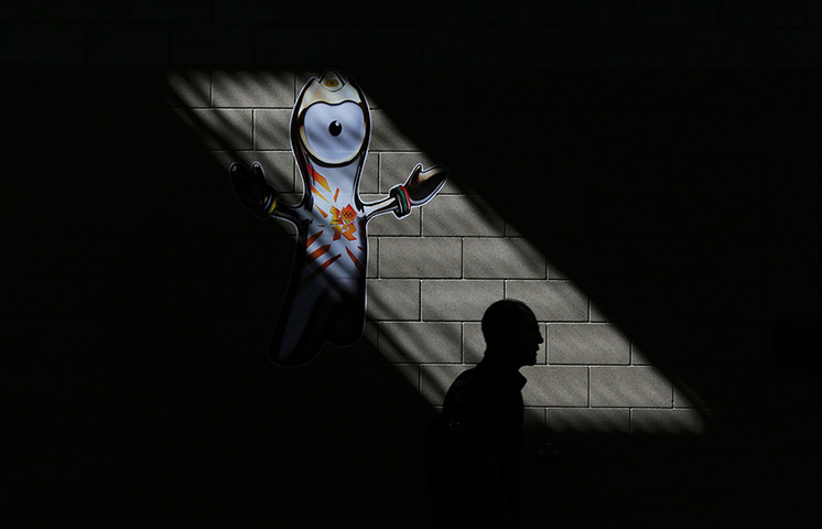 Olympic week update: A man walks past a poster showing mascot 