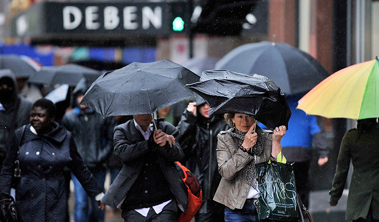Week in Business: Pedestrians walk through heavy rain along Oxford Street