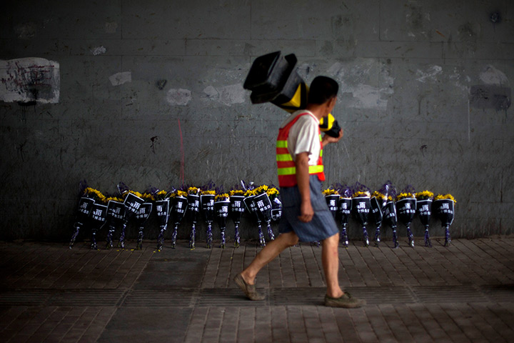 24 hours in pictures: A roadworker walks past flowers placed under a bridge