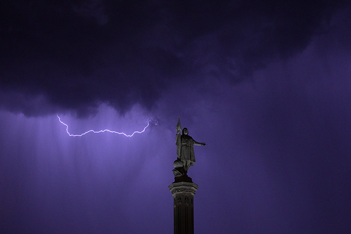 24 hours in pictures: Lightning is seen in the sky above the Christopher Columbus monument