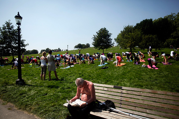 24 hours in pictures:  A man reads a newspaper while a yoga class is held on Primrose Hill