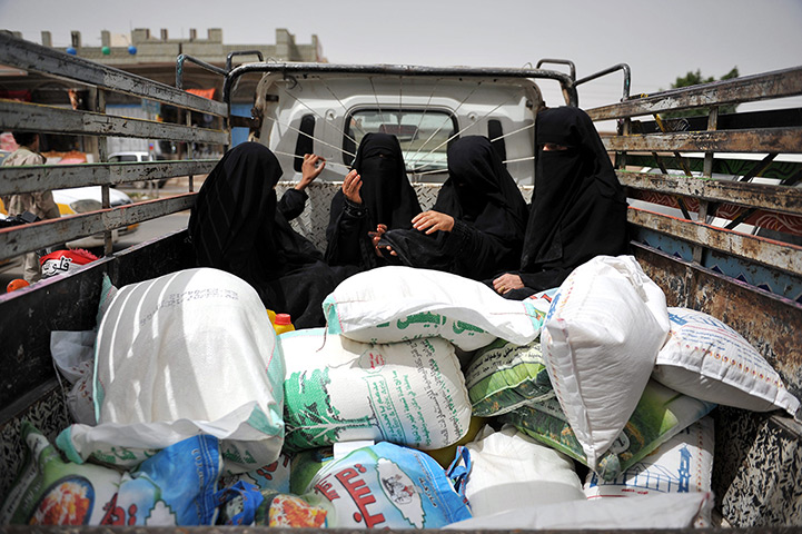 24 hours in pictures: Yemeni women sits next to sacks of food aid on a truck