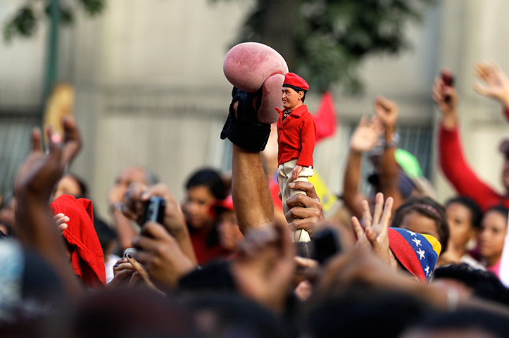 24 hours in pictures: A supporter holds up a Hugo Chavez  doll
