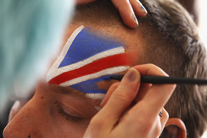 Athlete's final day: An athlete has his face painted in the village 