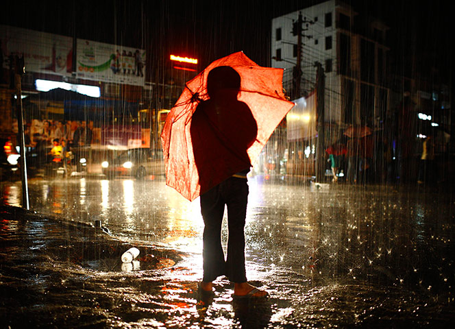 24 hours: A girl with her umbrella waits to cross the road during rainfall