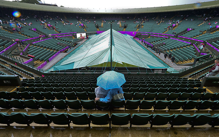 Olympic venues: A couple shelters from the rain under an umbrella  at Wimbledon