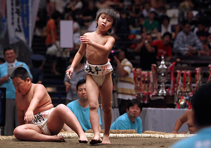 24 hours: Tokyo, Japan: A fourth grade pupil walks back across a sumo ring
