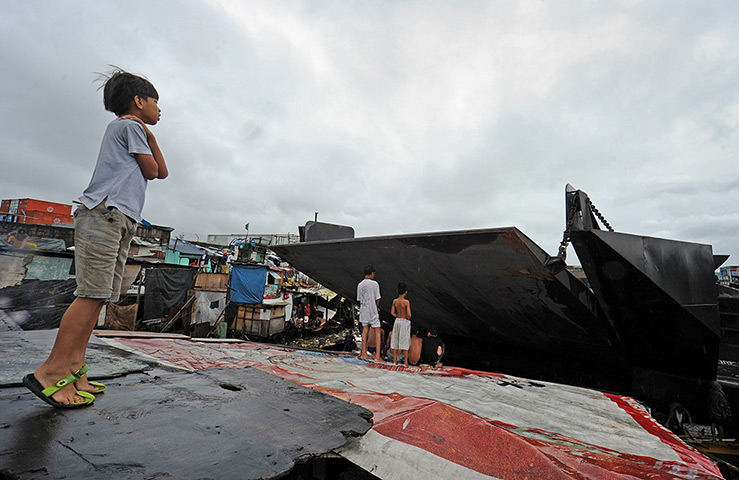 24 hours: Manila, Philippines: Boys look at the bow of one of two barges