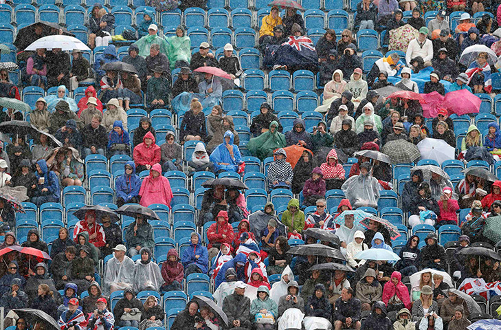 Olympic empty seats : Spectators shield themselves from rain at Greenwich Park