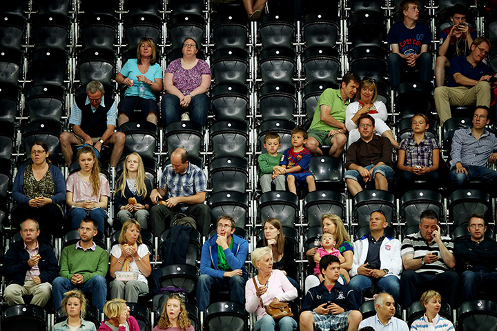 Olympic empty seats : Two boys share a seat amongst empty one at a Basketball match