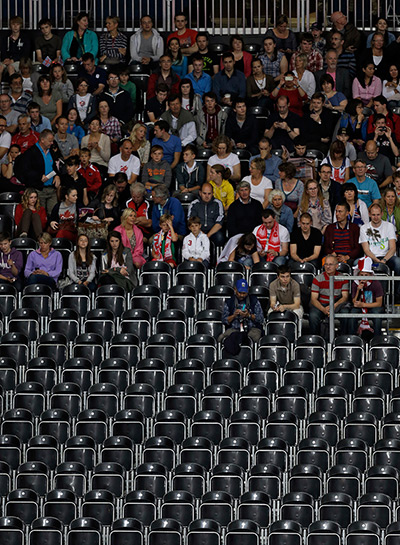 Olympic empty seats : Spectators sits in the back rows of empty seats during a men's volleyball