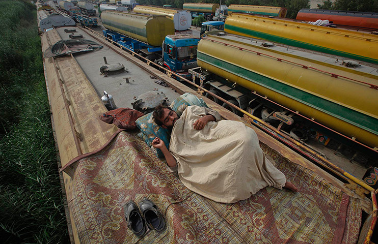 Picture desk live: Truck driver sleeps on the roof of a fuel tanker in Karachi