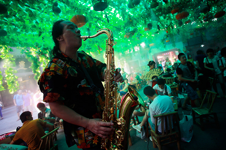 24 hours: Shanghai, China: A local saxophonist entertains people 