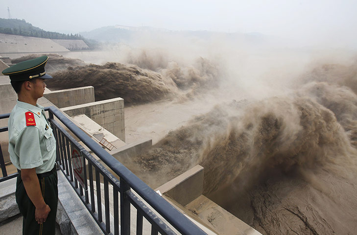 24 Hours: A paramilitary guard watches water being released from the Xiaolangdi dam