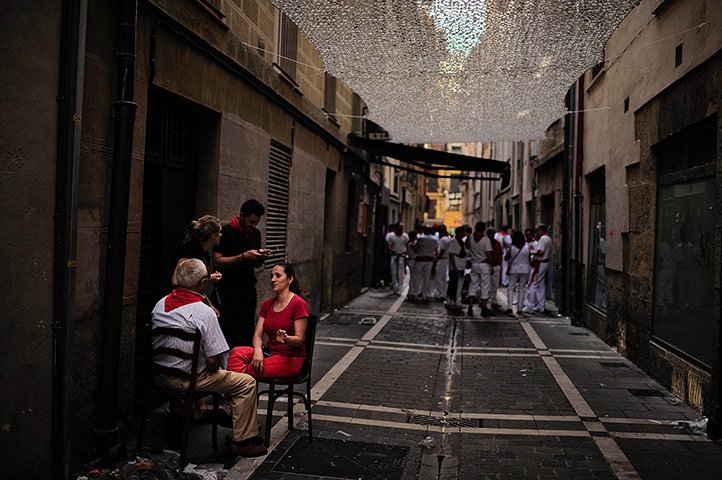 Pamplona: A couple talk in an old street while ''pamplonicas'' revelers enjoy the day