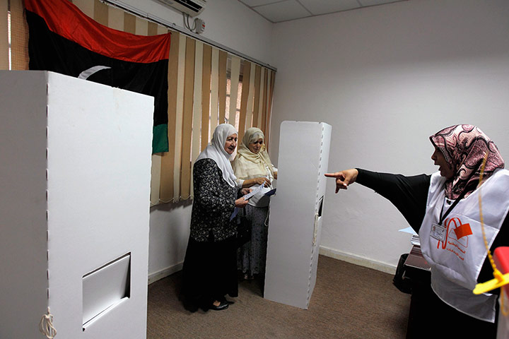 Libya Elections: An election commission worker tells two Libyan women to use separate booths
