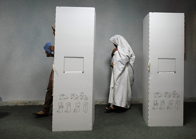 Libya election: A woman walks past a ballot booth at a polling station in Tripoli
