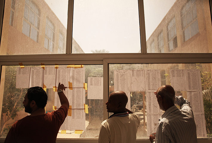 Libya election: Men look for their names on a voters list at a polling station in Tripoli