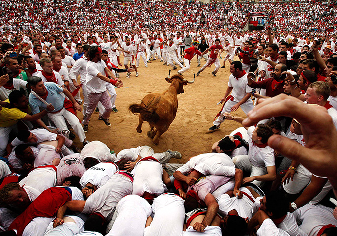  24 hours: Pamplona, Spain: A bull jumps over revellers in a bullring