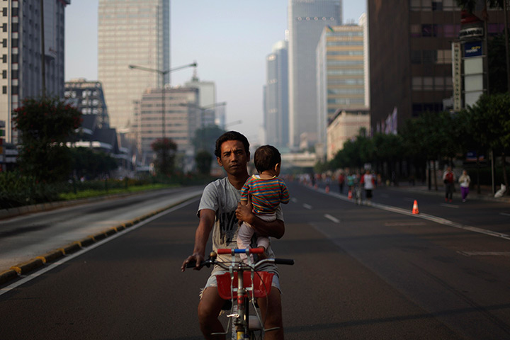  24 hours: Jakarta, Indonesia: A father holds his child while riding a bicycle 