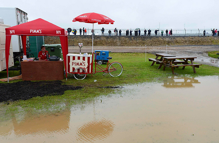 Summer rain: A man selling Pims sits in the rain at Silverstone circuit