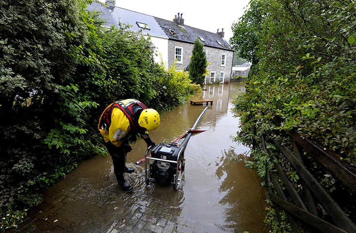 Summer rain: A member of the fire services mans the pump outside a property