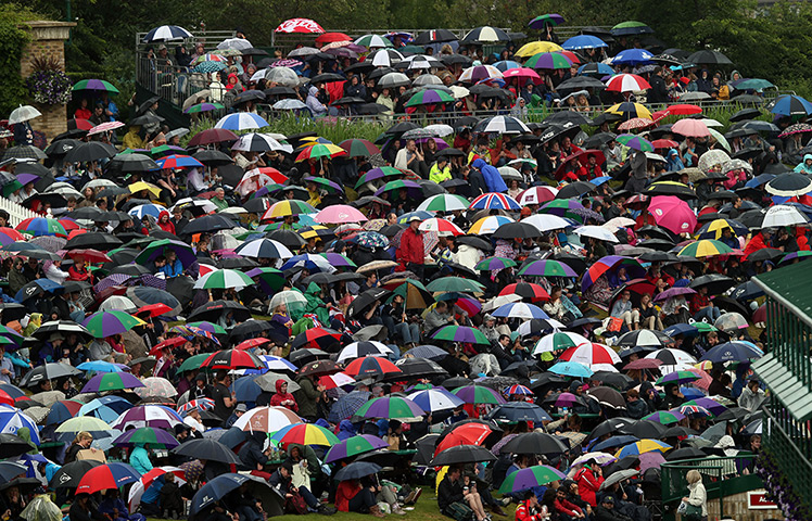 Summer rain: Tennis fans shelter from the rain at Wimbledon