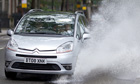 A car drives through a large puddle after heavy rain
