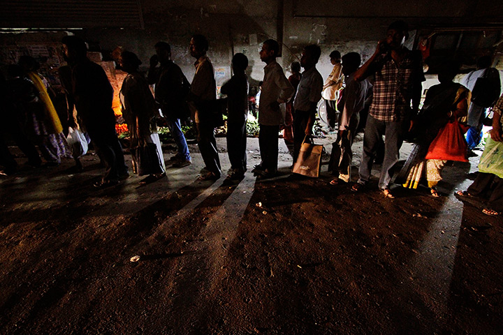 India blackout ends: Commuters wait for a bus on a street illuminated with vendor's kiosks