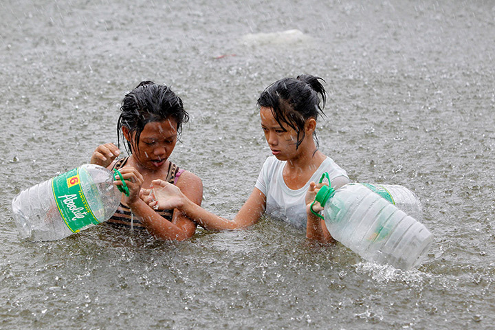 24hours in pictures: Girls wade on a flooded street to buy drinking water during heavy downpour