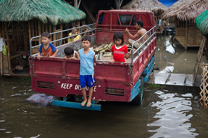 24 hours in pictures:  Children look out from the back of a truck standing in floodwaters