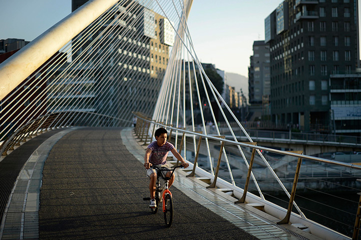 24 hours in pictures: A boy cycles across the Zubizuri (White Bridge) pedestrian bridge,