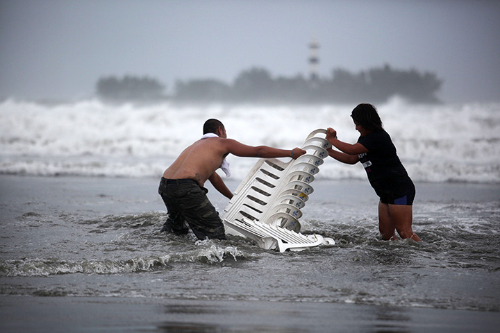 24 hours in pictures: Vendors recover their chairs after high waves during a storm