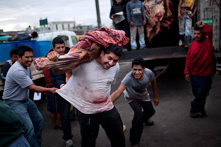 24 hours in pictures: Meat workers joke with their colleague as he carries meat from a truck