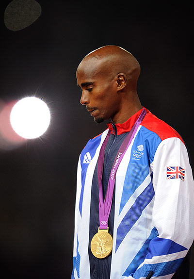 team gb gold: A thoughtful looking Mo Farah stands on the podium 