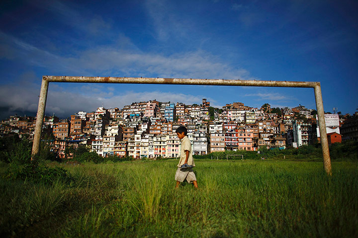 24 hours : A boy walks past a football post in front of the ancient city of Kirtipur